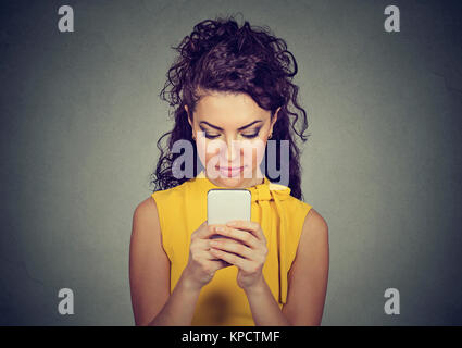 Giovane donna bellissima immersa in utilizza lo smartphone cerca focalizzata sullo schermo. Foto Stock