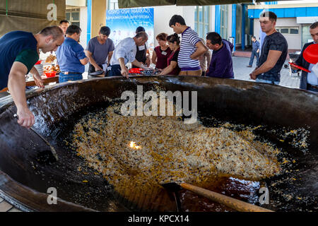 Servire gli uomini PLOV (il piatto nazionale) da un grande calderone presso l'Asia Centrale del centro di Plov, Tashkent, Uzbekistan Foto Stock