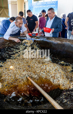 Servire gli uomini PLOV (il piatto nazionale) da un grande calderone presso l'Asia Centrale del centro di Plov, Tashkent, Uzbekistan Foto Stock