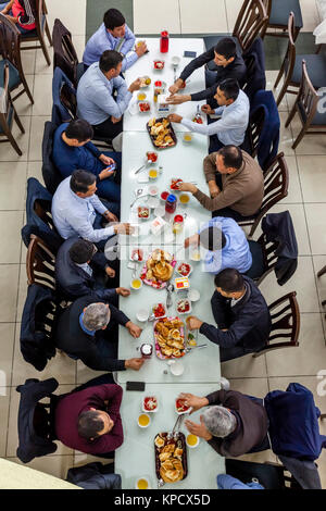 Un grande gruppo di uomini uzbeki mangiare PLOV (il piatto nazionale) presso l'Asia Centrale del centro di Plov, Tashkent, Uzbekistan Foto Stock