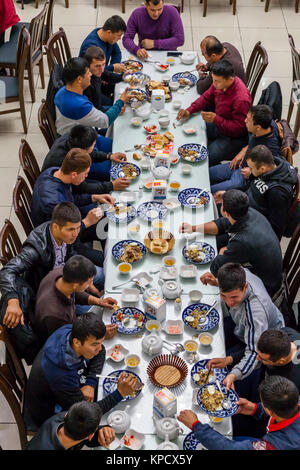 Un grande gruppo di uomini uzbeki mangiare PLOV (il piatto nazionale) presso l'Asia Centrale del centro di Plov, Tashkent, Uzbekistan Foto Stock