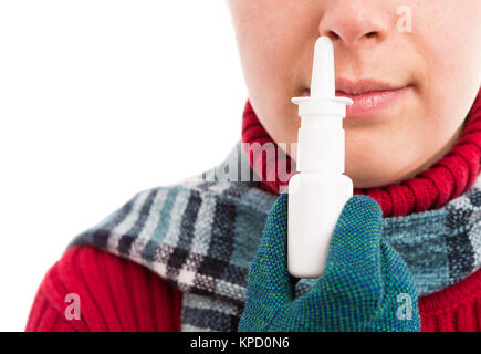 La donna a freddo utilizzando uno spray nasale o tenendolo vicino al naso indossando vestiti caldi con sciarpa e guanti Foto Stock