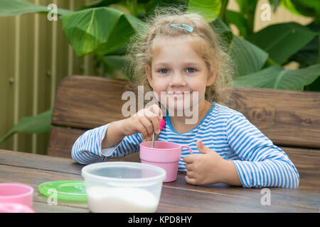 Quattro anni di ragazza nel tè interferisce con lo zucchero per la prima colazione Foto Stock