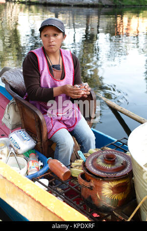 Xochimilco, Città del Messico, Messico - 2017: una donna in atrajinera (un tipo di locale di barca) vende cibo locale per persone in altre trajineras sul canale della città Foto Stock