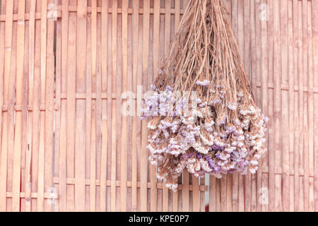 Bouquet di fiori secchi appesi su sfondo di bambù Foto Stock