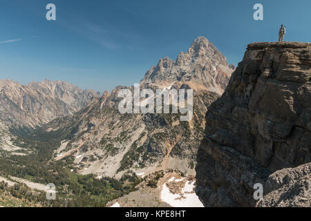 Un escursionista sorge su una scogliera di fronte Grand Teton in Grand Teton National Park, Wyoming Foto Stock