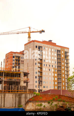 Sagome di gru a torre contro il cielo di sera. Casa in costruzione. Skyline industriale con case in costruzione e gru a torre ancora Foto Stock