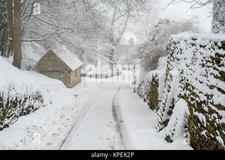 Coperta di neve ripida strada nel villaggio di Snowshill in dicembre. Snowshill, Cotswolds, Gloucestershire, Inghilterra Foto Stock