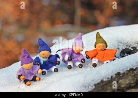 Quattro gnomi piccoli si siedono nella neve Foto Stock