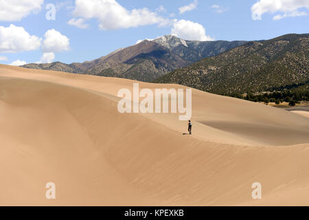 Escursioni sulle dune di sabbia - un turista è escursionismo su una duna di sabbia sulla cresta di una giornata di primavera a Great Sand Dunes National Park, COLORADO, Stati Uniti d'America. Foto Stock