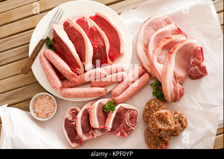 Assortimento di carne cruda su di un tavolo di legno Foto Stock