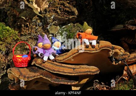 Quattro gnomi con uova di Pasqua siedono su un fungo dell'albero Foto Stock