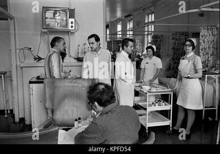 NHS 1970 UK, dottori Ward Round al Charing Cross Hospital di Londra. I pazienti hanno permesso di vagare all'interno del reparto, mangiare i loro pasti e guardare la televisione. Il carrello dei pasti è preso intorno ai pazienti da uno degli infermieri junior. British National Health Service 1972. HOMER SYKES Foto Stock