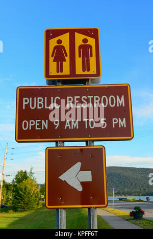 Toilette pubblica ore segno e direzione in speculatore, NY USA presso la spiaggia privata sul lago di piacevole di Adirondack Park. Foto Stock