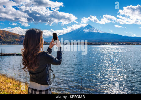 Donna utilizzare il telefono cellulare per scattare una foto al Fuji montagne lago Kawaguchiko in Giappone. Foto Stock