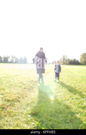 Una inquadratura sfocata di madre e figlio di quattro anni camminare sul campo britannico al sole Foto Stock