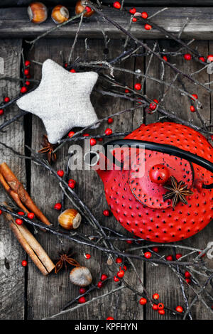 Red bollitore in metallo,rami con bacche su sfondo di legno Foto Stock