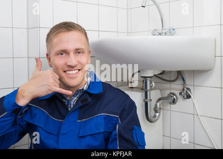 Felice Plumber rendendo Call Me gesto Foto Stock