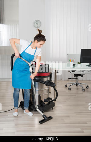 Un esile giovane donna, 22 anni, vestito di un lungo e stretto raccordo  abito da sera, pulisce il pavimento con un aspirapolvere verticale. Un  sottile la pulizia l Foto stock - Alamy