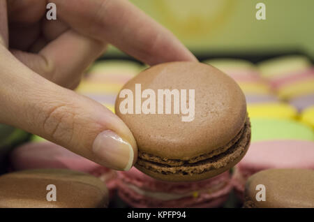 Mano femminile prendendo gustosi amaretti colorati da box Foto Stock