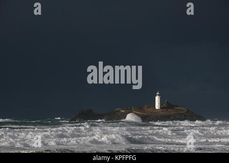 Godrevy Island e il faro, Cornwall nella luce solare contro il cielo scuro di un avvicinamento invernali tempesta. Foto Stock