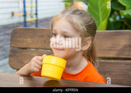 Quattro anni di ragazza sorridente tenendo un bicchiere di succo di frutta Foto Stock