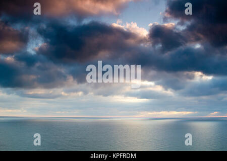 Ostsee im Sommer mit Sonne im Gegenlicht und Reflexionen,Untergehende Sonne bestrahlt Äste und Steine im Meerwasser Foto Stock