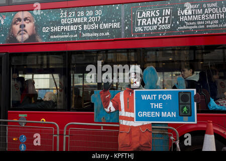 La figura di un lavoratore edile attenzione ai pedoni di attraversare in modo ragionevole, e il passaggio di un bus, il 12 dicembre 2017, a Londra Inghilterra. Foto Stock