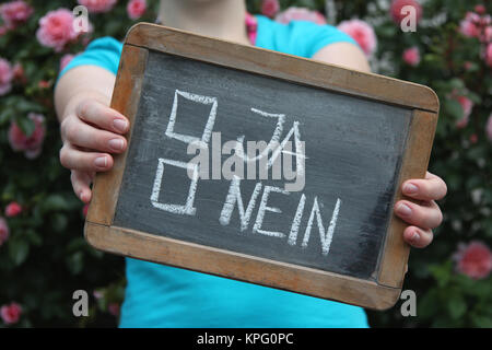 JA NEIN/ (sì/no in tedesco) scritto con un gessetto su ardesia mostrato dalla giovane femmina Foto Stock