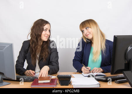 Le ragazze in ufficio guardato ogni altro, uno di loro parla al telefono e la scrittura in un notebook Foto Stock