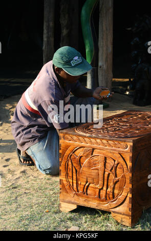 Il Mozambico, il mercato delle pulci, uomo africana la lucidatura di un legno intagliato kist a Ponta do Ouro Foto Stock