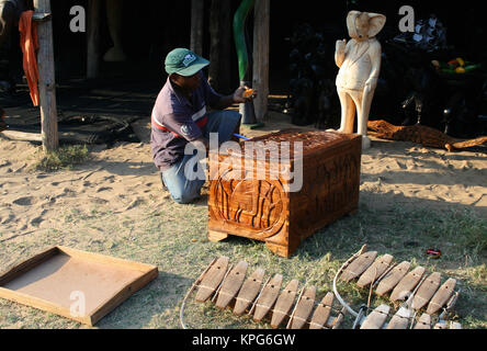 Il Mozambico, il mercato delle pulci, uomo africana la lucidatura di un legno intagliato kist a Ponta do Ouro Foto Stock