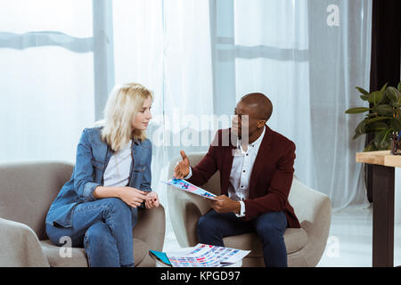 Interracial fotografi avente discussione mentre scegliendo le foto insieme in ufficio Foto Stock