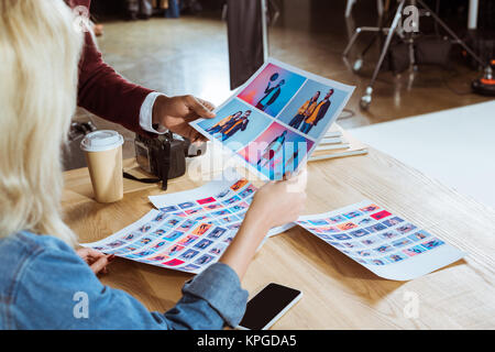 Ritagliato colpo di fotografi multiculturale scegliendo le foto insieme al lavoro in ufficio Foto Stock