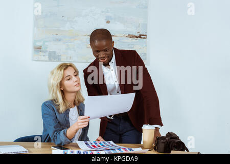 Fotografi multiculturale scegliendo portfolio insieme al lavoro in ufficio Foto Stock