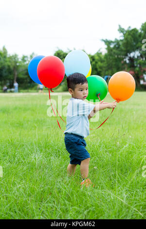 Asian baby boy gioca con il suo mazzetto di palloncino Foto Stock