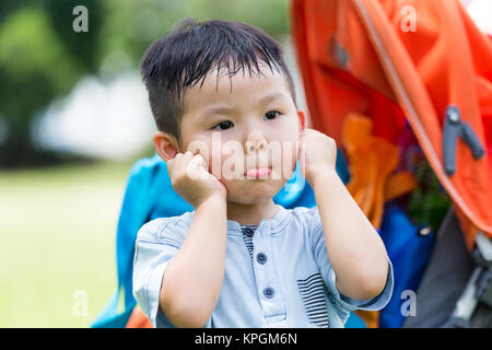 Ragazzo carino sentirsi colpevole a mano sul suo orecchio Foto Stock