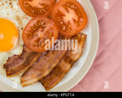 Uova pancetta e pomodoro il cibo a colazione contro un sfondo rosa Foto Stock