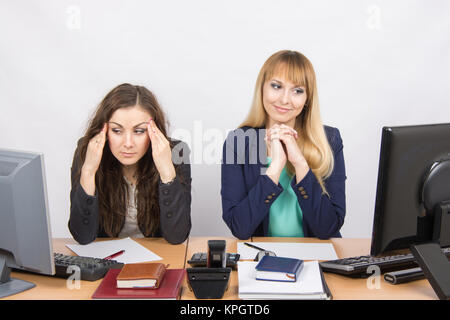 La situazione in ufficio - ragazza felicemente guardando lo schermo di un computer e di una ragazza con un mal di testa guardando lo schermo Foto Stock