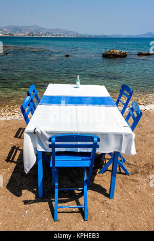 Tavoli con sedie in una tradizionale taverna Greca Kolympia nella cittadina sulla costa dell'isola di Rodi, Grecia. Foto Stock