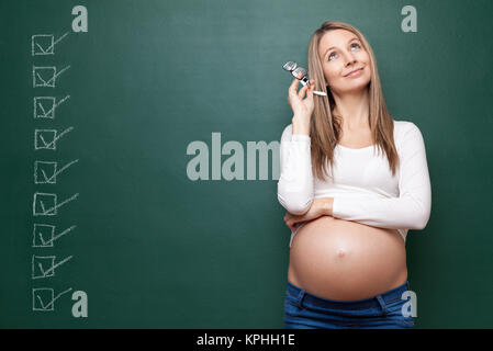 Donna incinta e una lavagna con copyspace Foto Stock