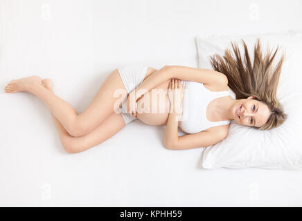 Donna incinta rilassante sul letto Foto Stock