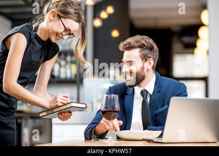 Cameriera prendendo un ordine dal proprietario Foto Stock