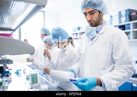 Gli scienziati di indossare abbigliamento protettivo lavorare in laboratorio. Foto Stock