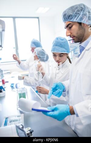 Gli scienziati di indossare abbigliamento protettivo lavorare in laboratorio. Foto Stock