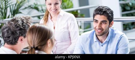 I colleghi avente incontro sul divano, giovane con tavoletta digitale. Foto Stock