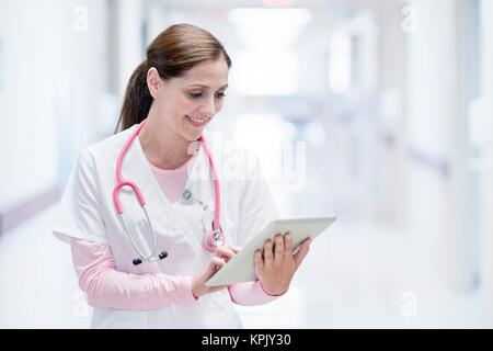 Infermiera in ospedale con tavoletta digitale, sorridente. Foto Stock