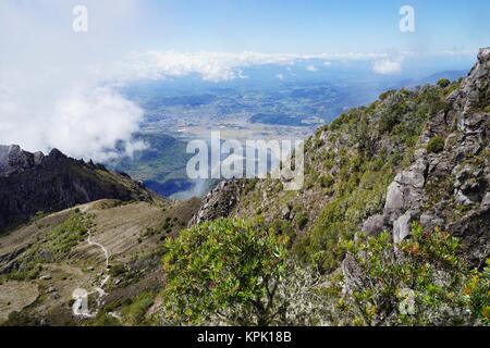 La vista dalla cima del vulcano Baru, Panama a valle con il sentiero discendente, cittadina in distanza e nuvole bianche Foto Stock