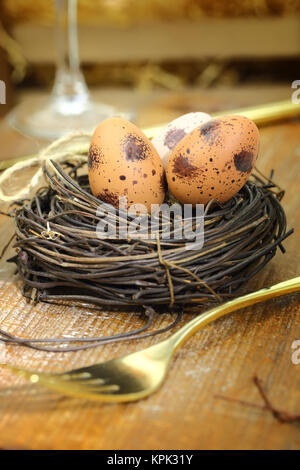 Uova di Pasqua nel nido e golden forcella sullo sfondo di legno Foto Stock