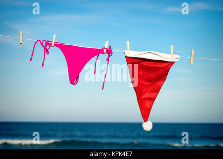 Tanga Bikini e Santa hat essiccazione su una spiaggia soleggiata, una fuga stagionale concept Foto Stock